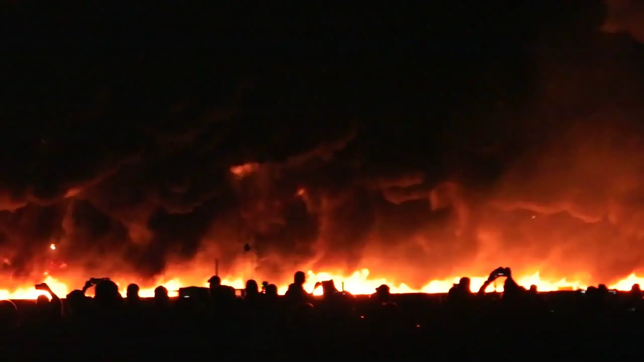 A pyrotechnic wall of fire explodes in front of the audience at the end of an air show