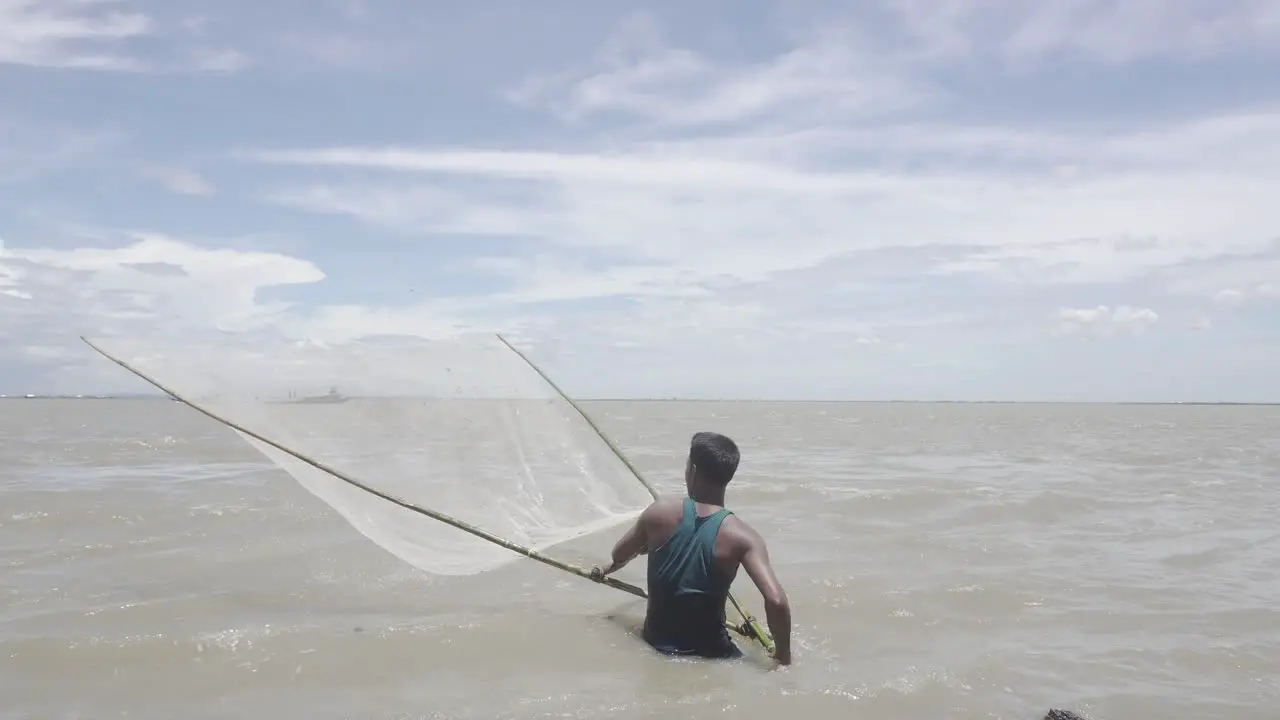 Wide shot of a Bangladeshi fisherman fishing in the river during the flood