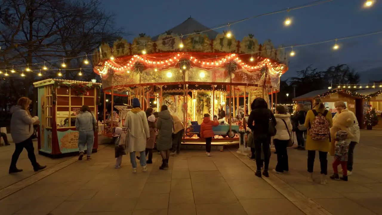 Parents standing in front of a carousel as their kids get on it at the Sofia Christmas Fest 2023