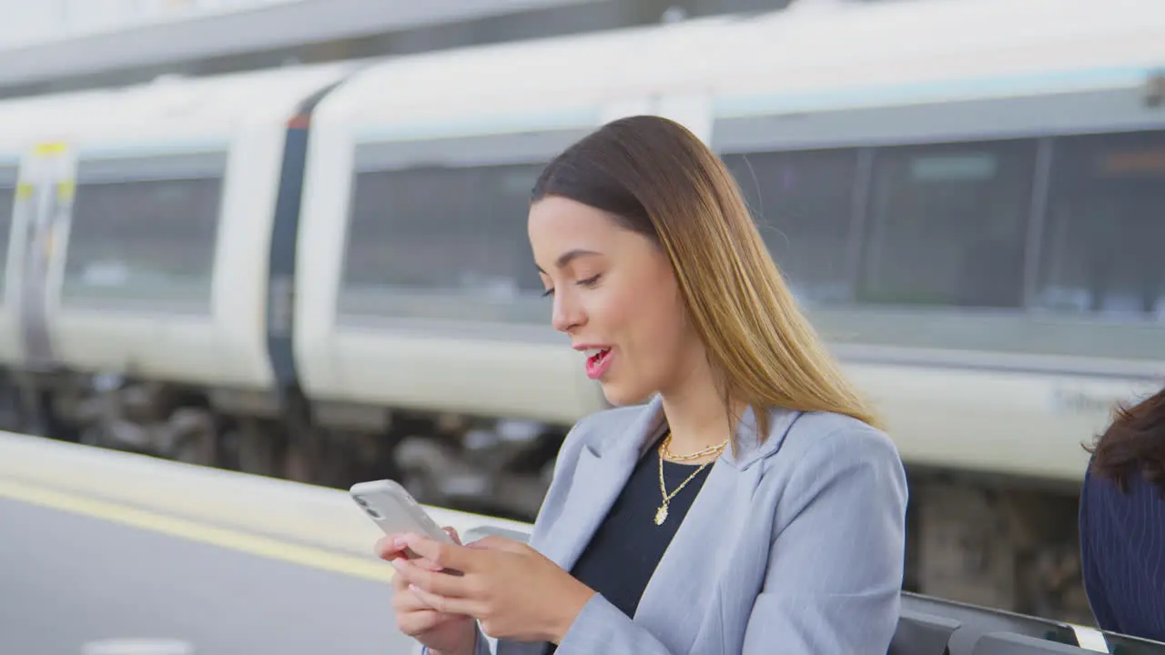 Businesswoman Waiting On Train Platform With Wireless Earbuds Answers Call On Mobile Phone