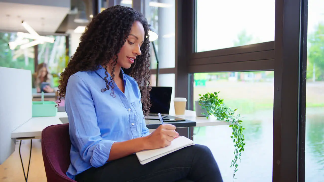 Businesswoman Working At Desk In Office Taking Call Talking Into Mic Of Mobile Phone