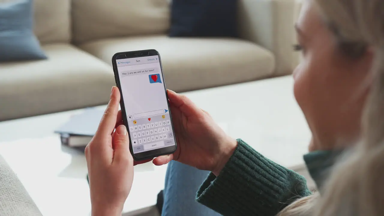 Close Up Of Woman Looking At Messages Arranging Romantic Date On Mobile Phone Messaging App