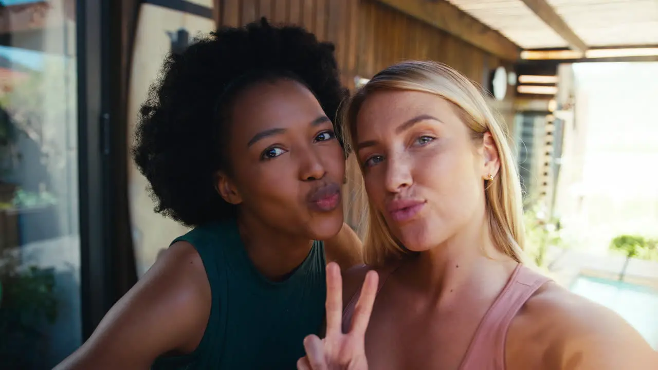 POV Shot Of Smiling Female Friends Outdoors At Home Posing For Selfie On Mobile Phone Together