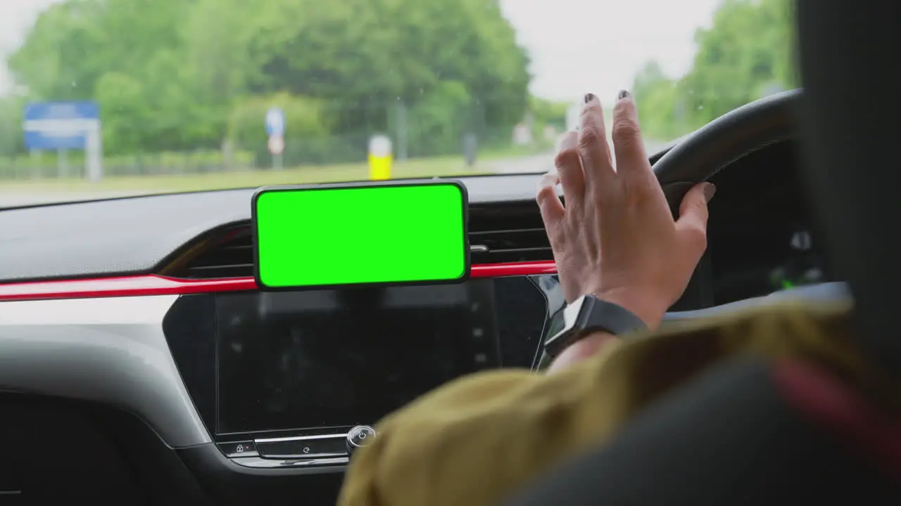 Close Up Of Female Driver With Hands Free Unit For Green Screen Mobile Phone Mounted On Dashboard