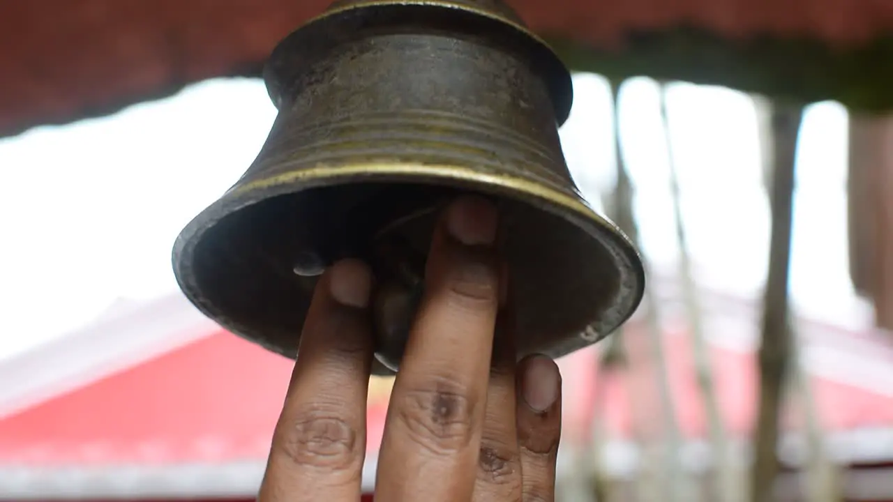 Visitor ringing bell hanging at temple ceiling