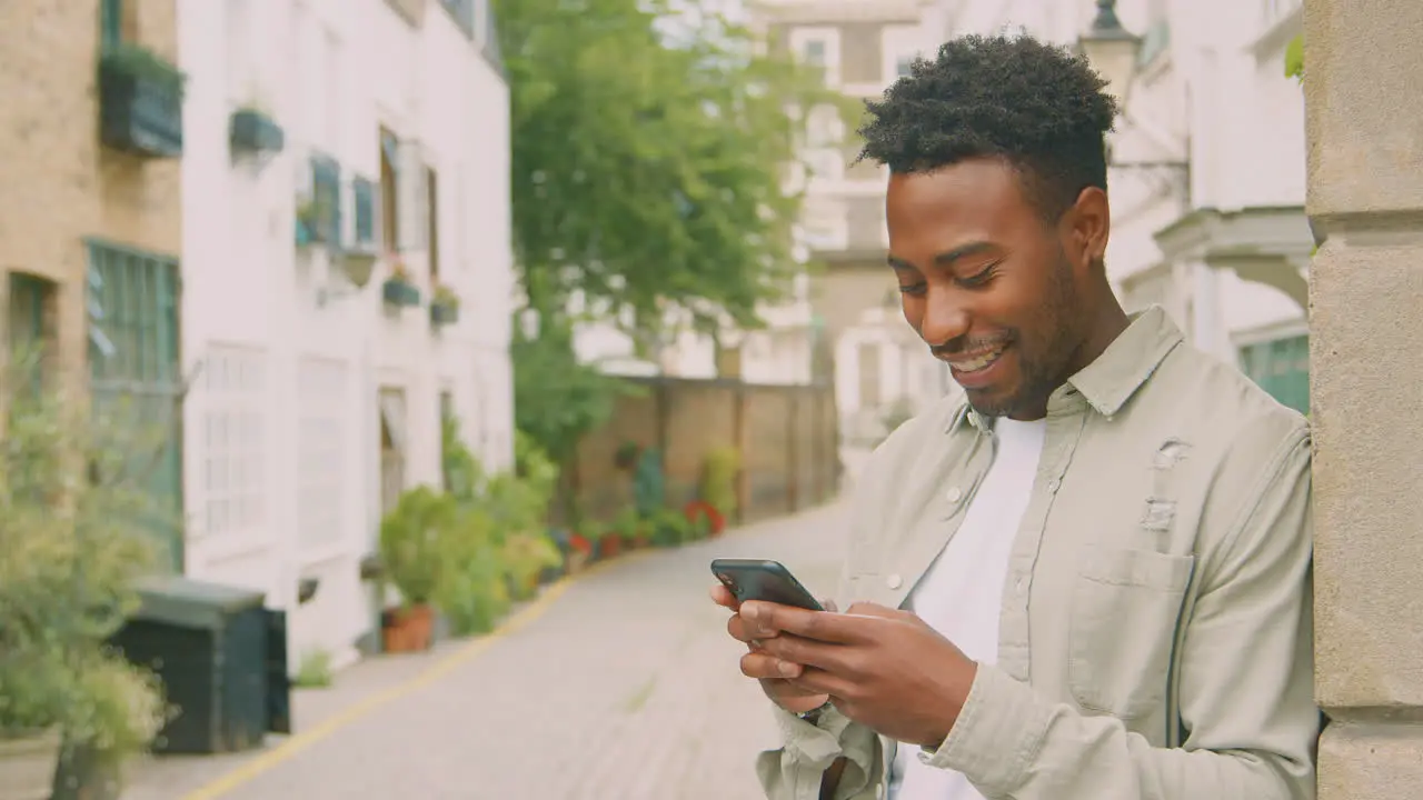 Young Male Vlogger Or Social Influencer Travelling Through City For Social Media Using Mobile Phone