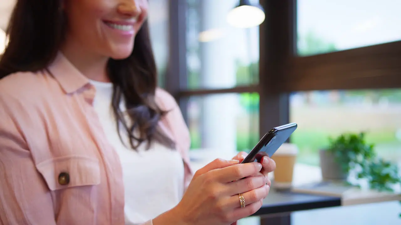 Close Up Of Businesswoman Sitting At Desk In Office Texting Or Browsing On Mobile Phone