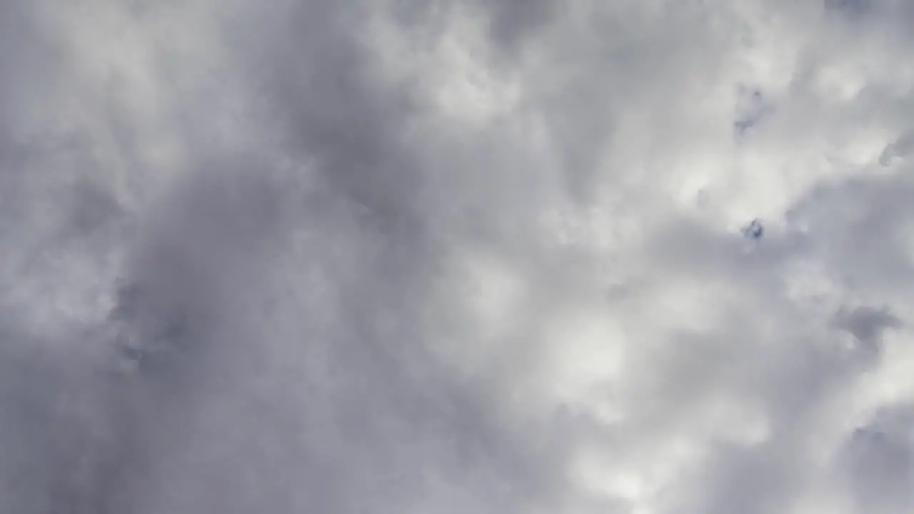 Stormy clouds move quickly up and across deep blue skies beyond time lapse