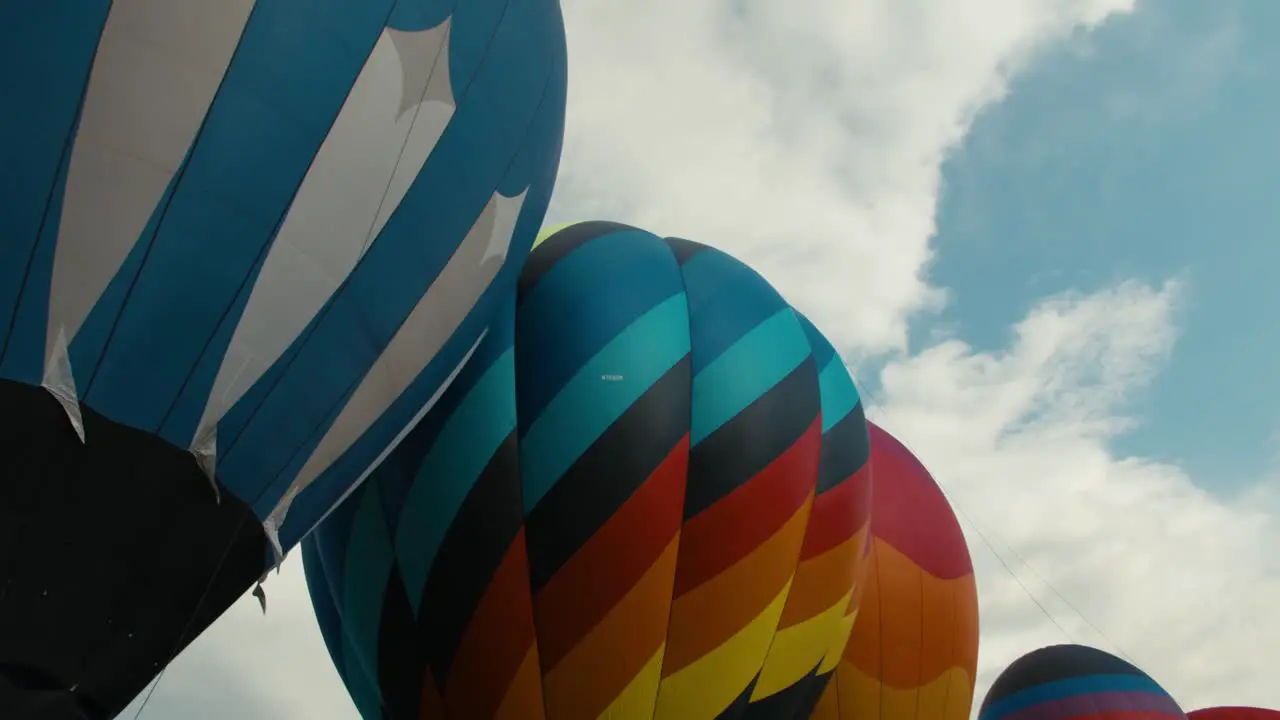 Colorful hot air balloons fully inflated and in a line row waiting to take off from the ground at sunrise or sunset with clouds in the background