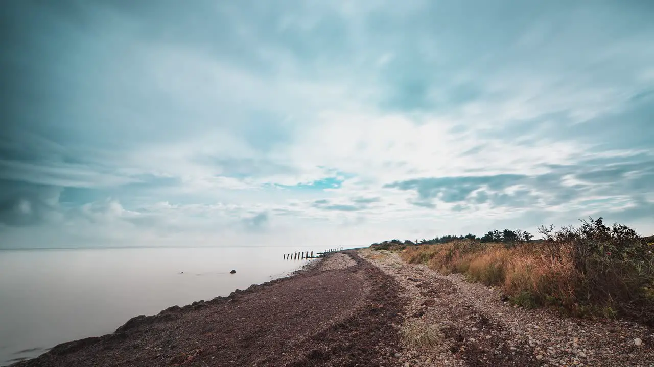 Fast-moving stormy clouds above the pebble beach in the timelapse video