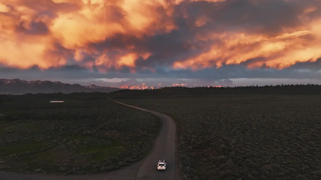 Car driving on a dirt road into a wild stormy sunset