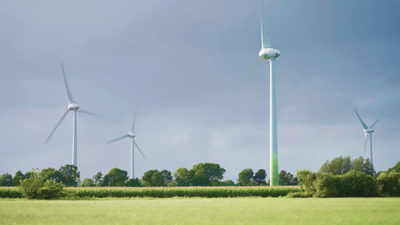 Gigantic rotating wind turbines in the lush green landscape