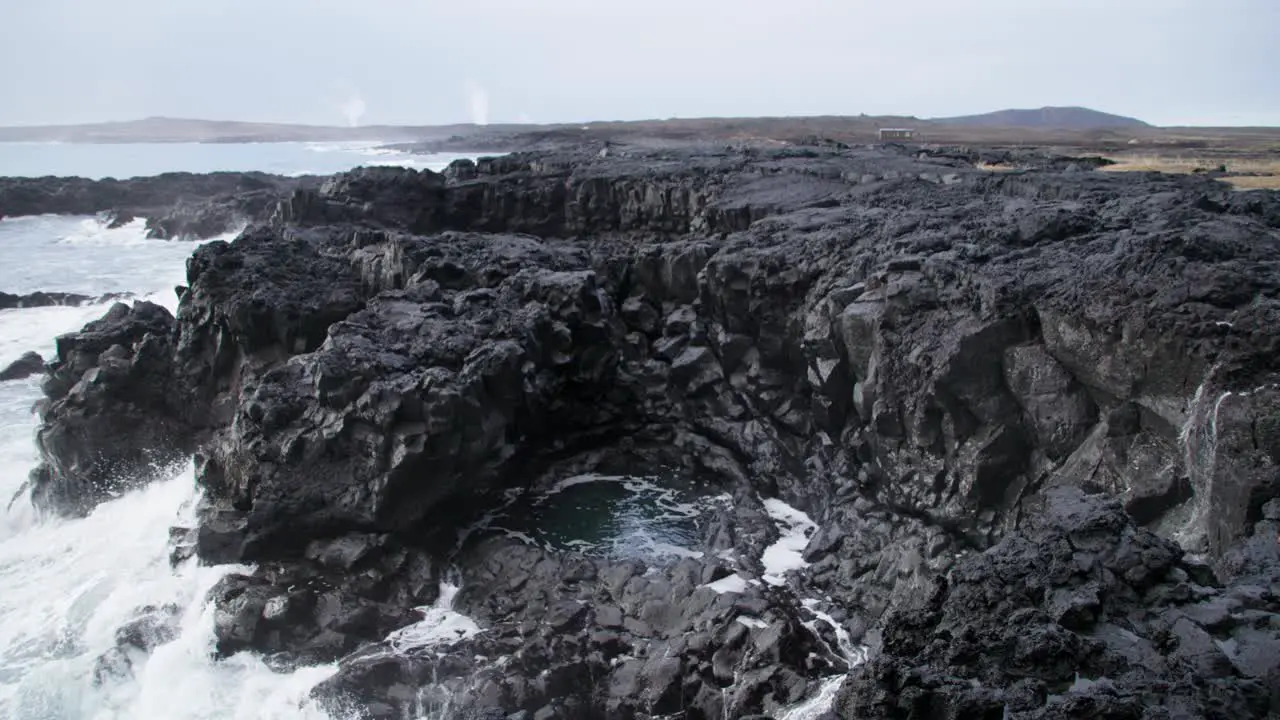 Rugged basalt shore line of Iceland with white foam wave splashing ocean blow hole