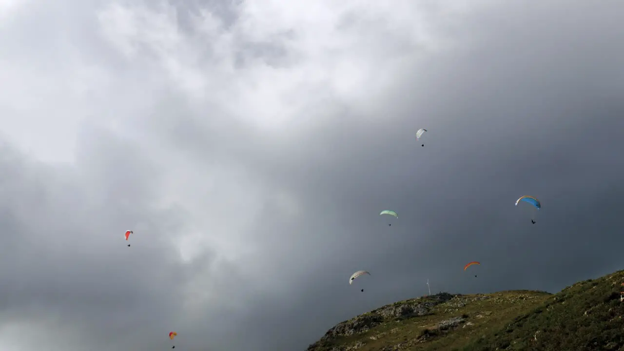 Group of paragliders gliding down mountain on a very cloudy day