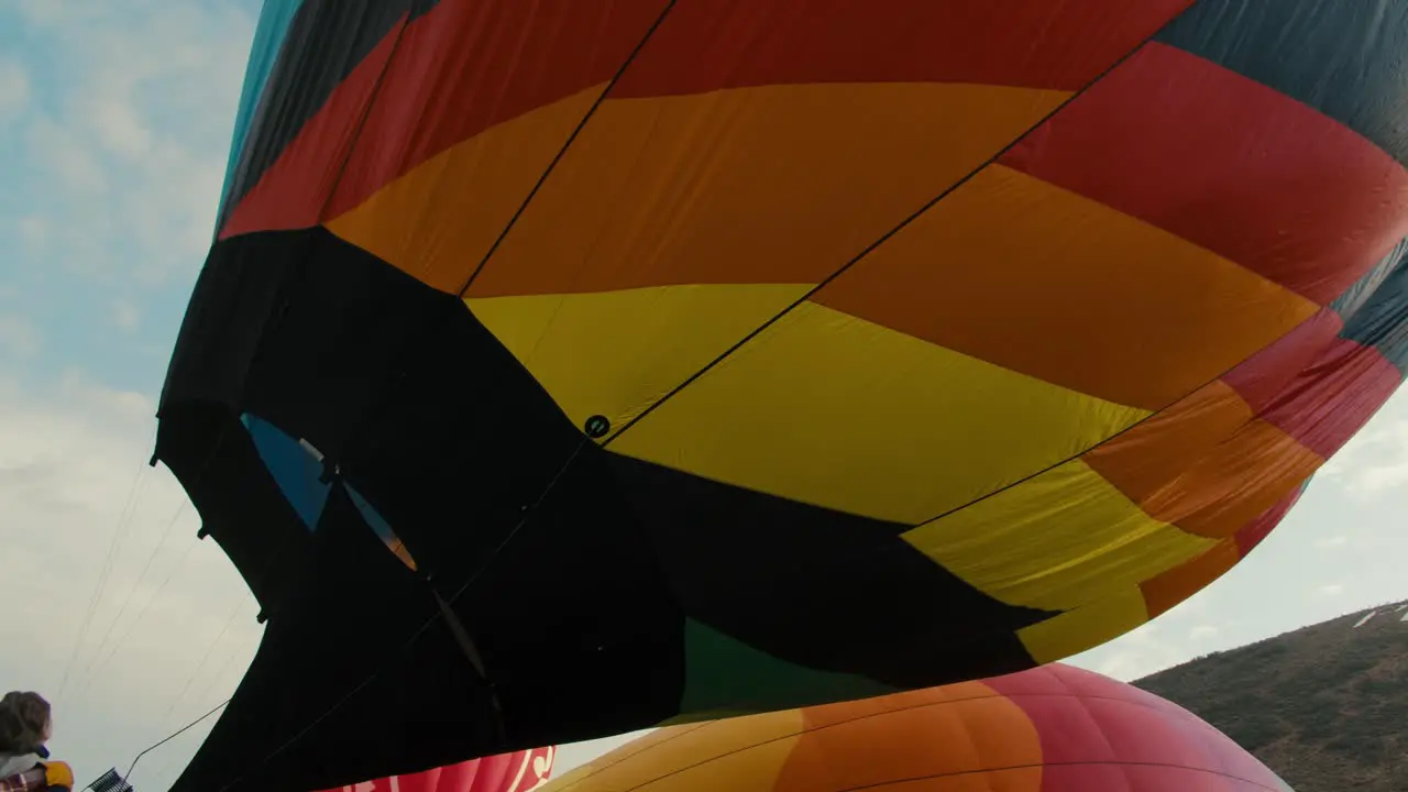 Side profile of flames inflating filling up colorful hot air balloon at sunrise in the cold winter morning