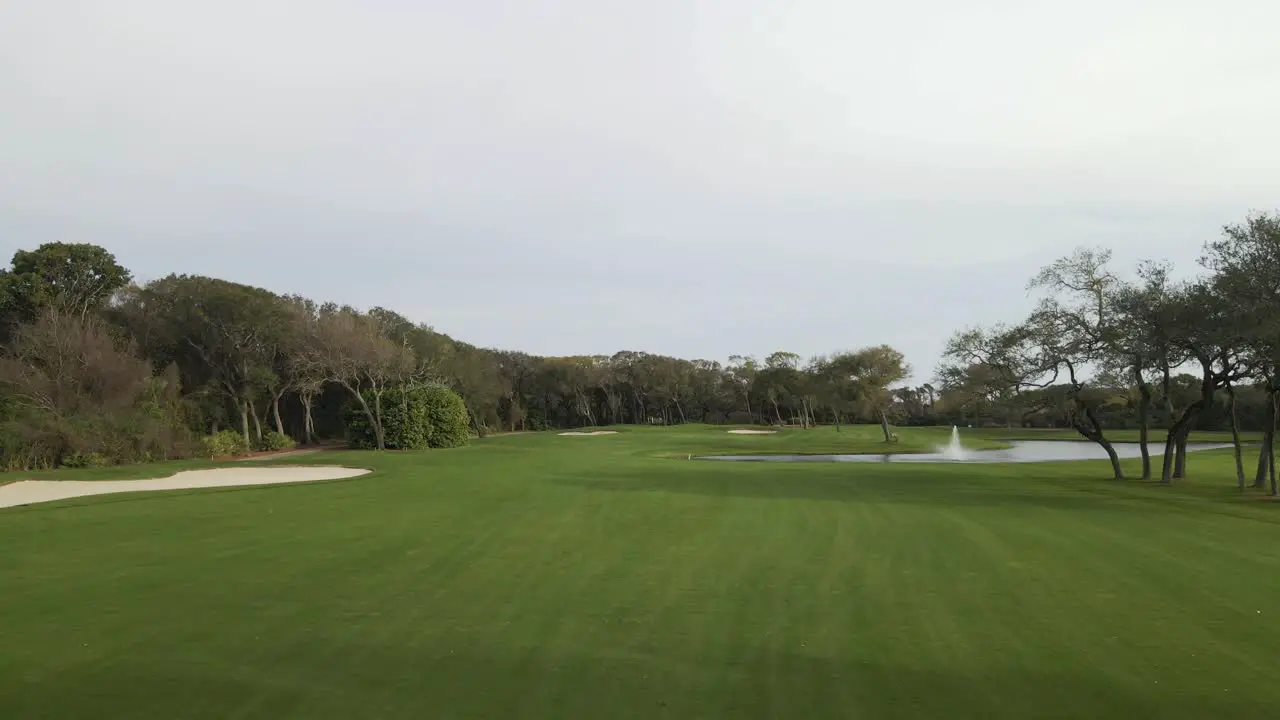 A push in drone shot over a Florida golf course with a pond and trees