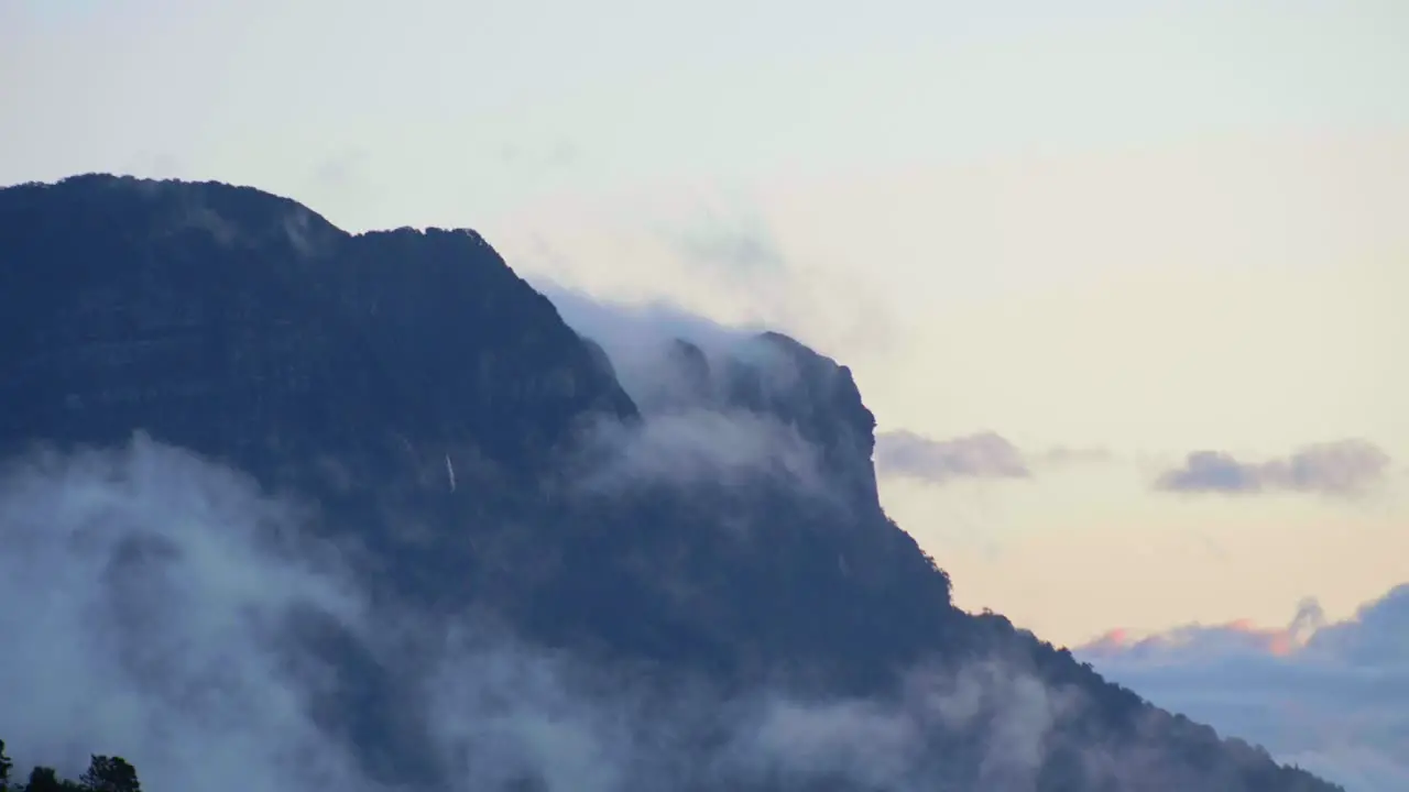 Spectacular footage capturing the mesmerizing sight of clouds gracefully gliding beneath a towering mountain revealing nature's grandeur and dynamic beauty