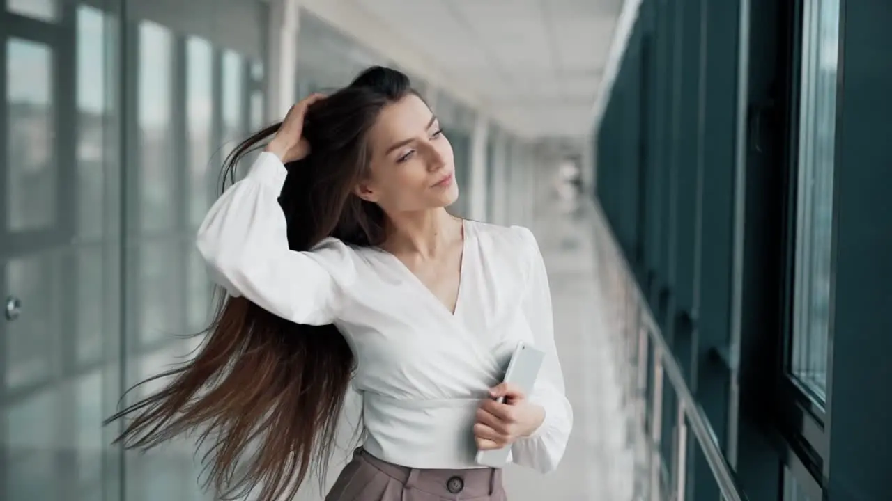 Stylish young woman with a tablet posing in a glass corridor