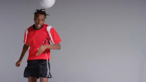 Young Male Footballer In Studio Running and Heading Ball 2