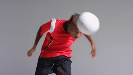 Young Male Footballer In Studio Running and Heading Ball 1