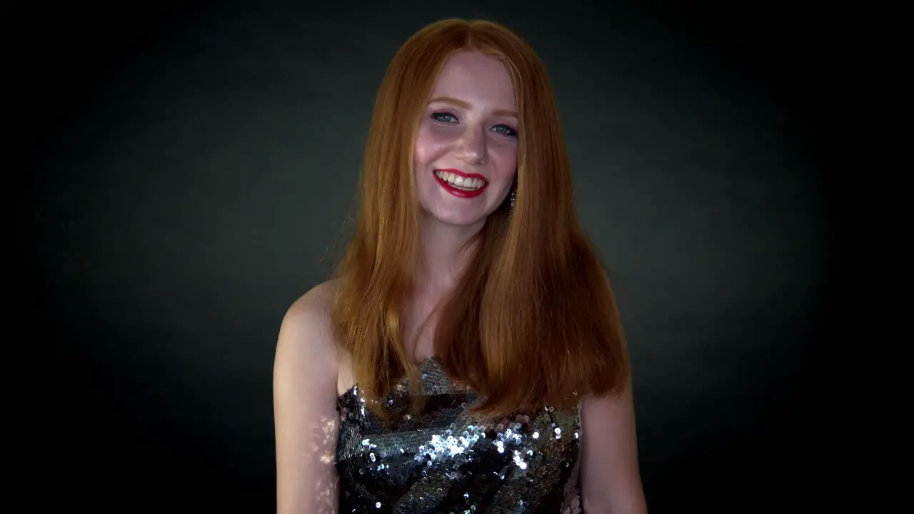 A young beautiful woman in shimmery dress all happy and joyous laughing and smiling looking towards the camera