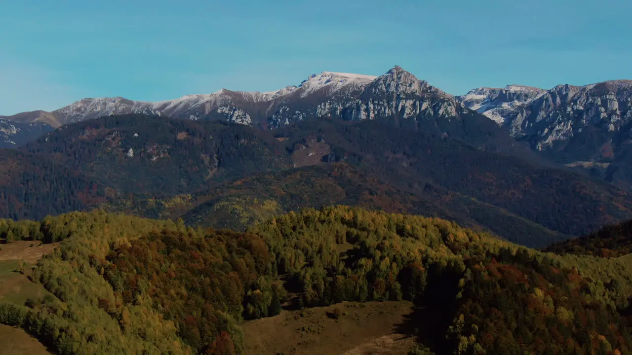 Aerial beautiful view with hills valleys and snowy mountain ridge on a clear sunny day close up