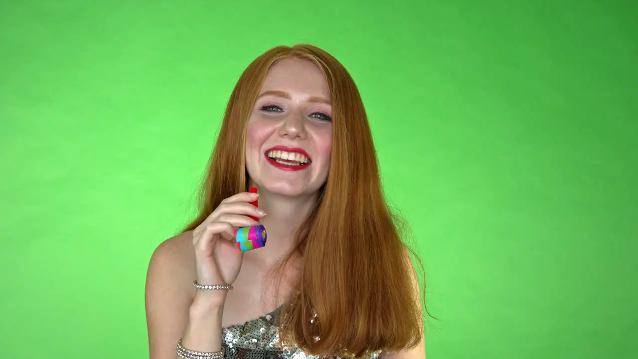 A young beautiful woman all dressed up laughing away and playing with a balloon whistle