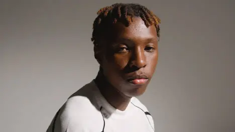 Studio Portrait Of Young Male Footballer Wearing Club Kit Sitting On Block 1