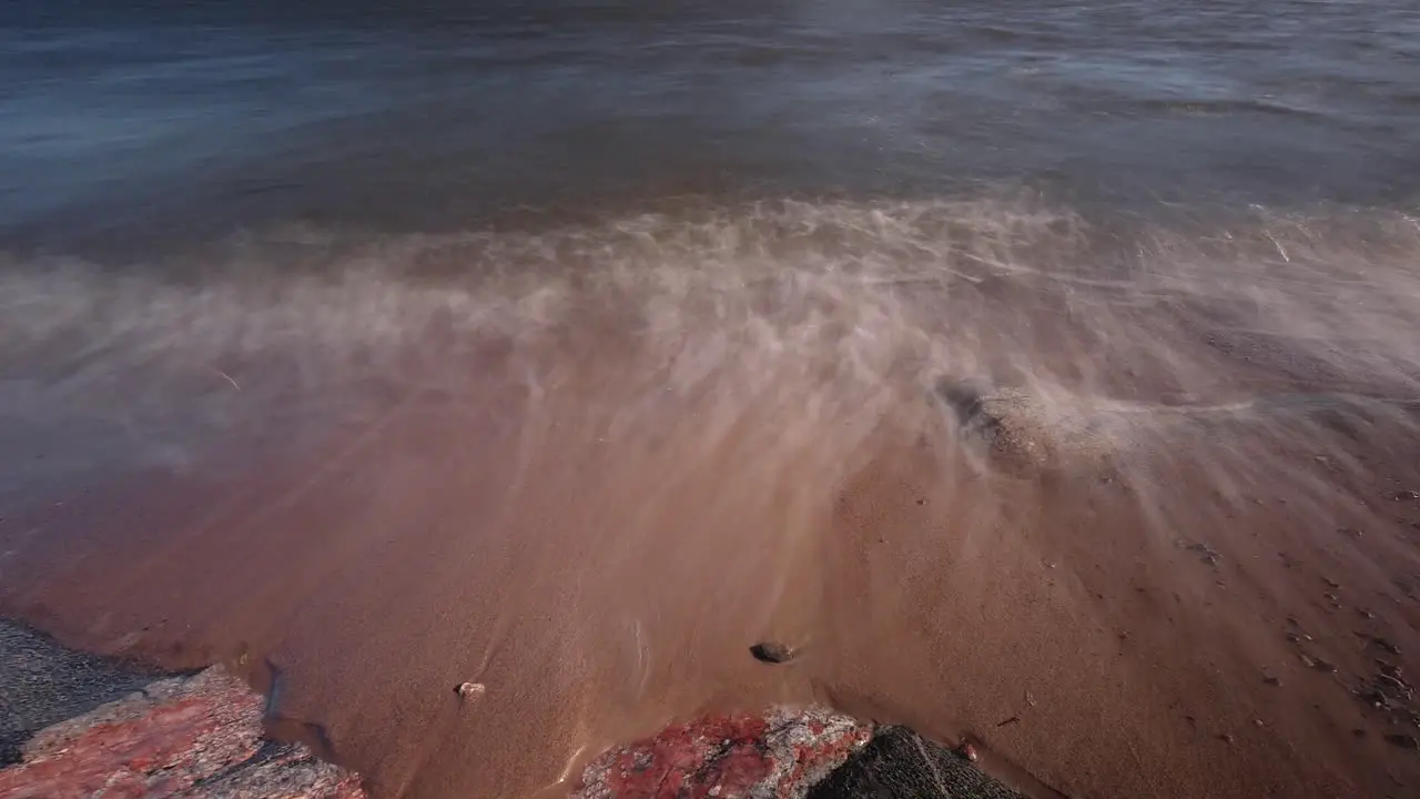 Time-lapse seashore close up with rocks backlit