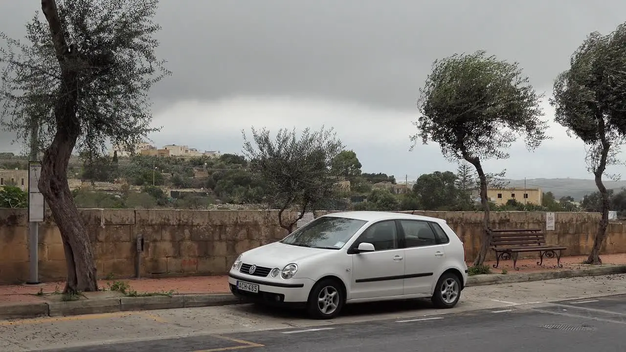 White Volkswagen Polo car parking on a street with an extreme storm coming and strong wind