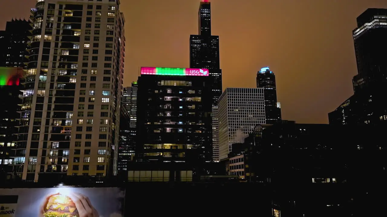 Aerial view rising in front of the Willis Tower from West Loop Gate cloudy night in Chicago