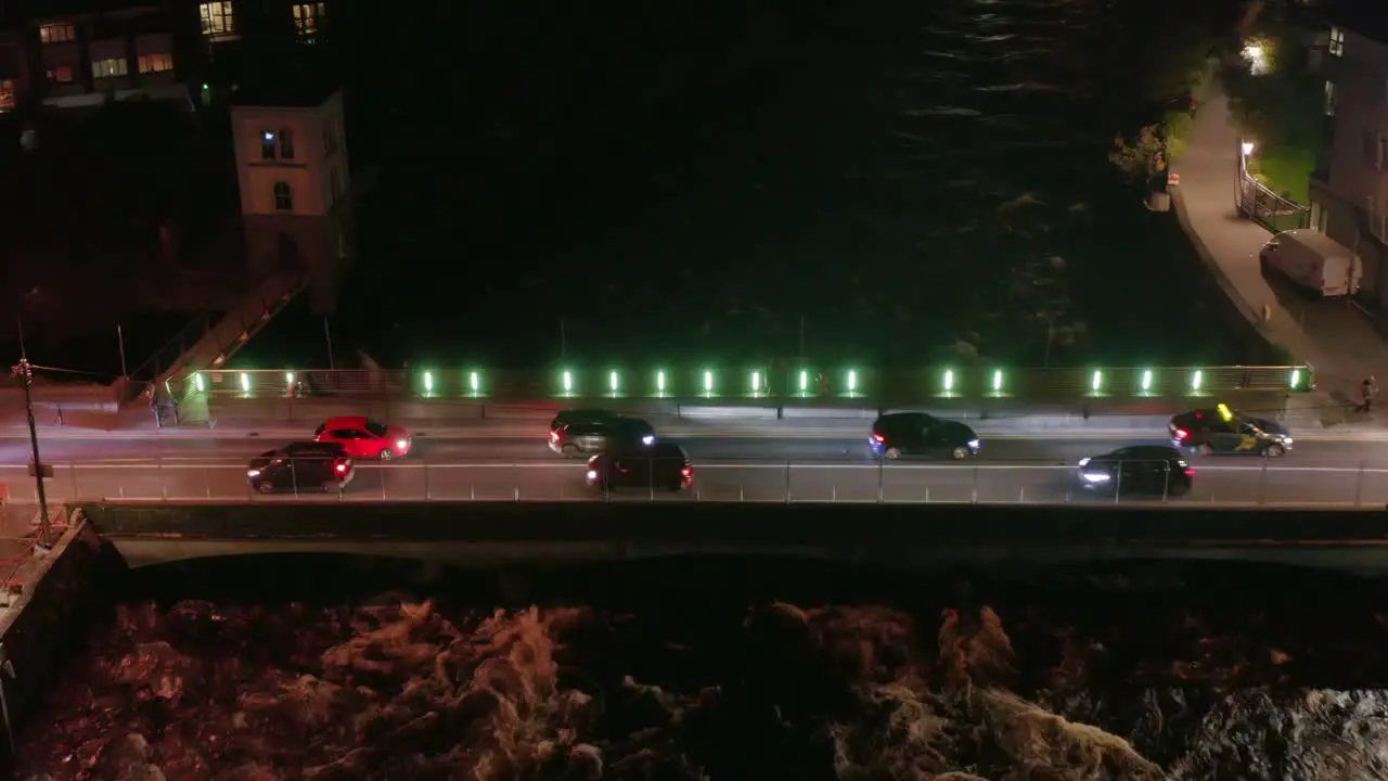 Bridge over a flowing river with traffic at nighttime