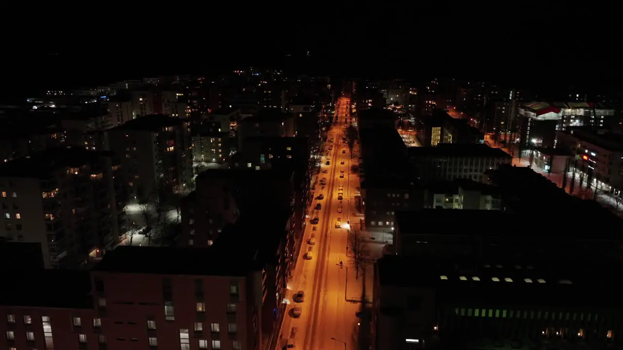 Cars parked on a street with orange lights in Lauttasaari Helsinki on a cold winter night aerial view