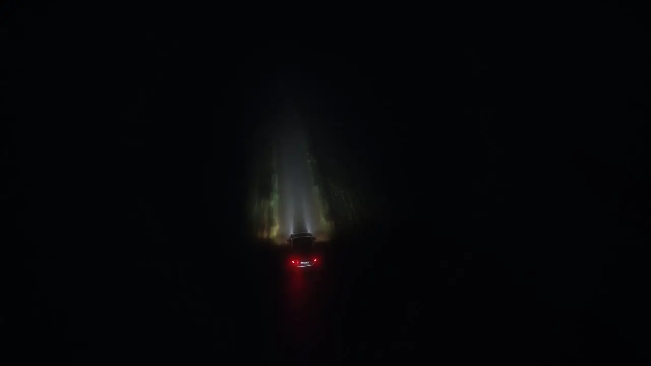 Car driving countryside road at night aerial drone following or tracking back view