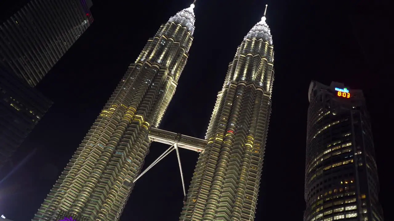 Quick establishing tilt up over beautiful Petronas Twin Towers with water show at night