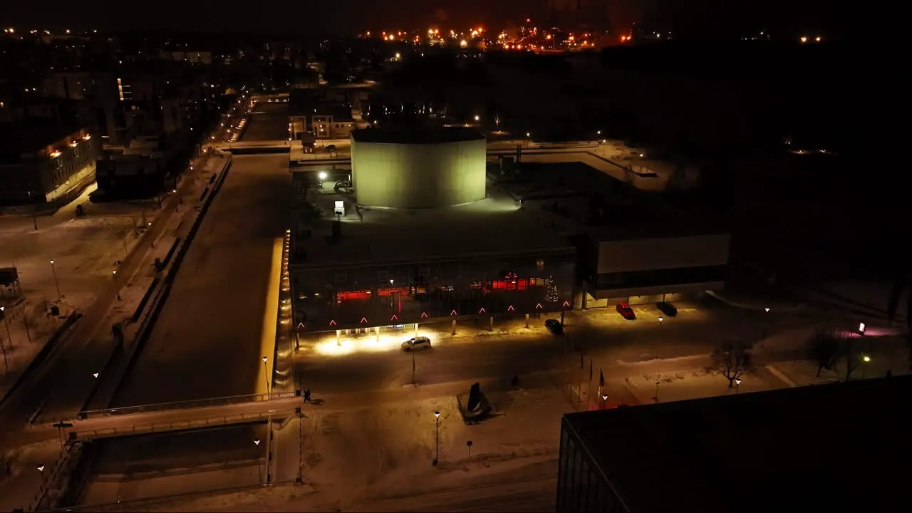 Drone shot away from the night lit Oulu Theatre winter evening in Finland