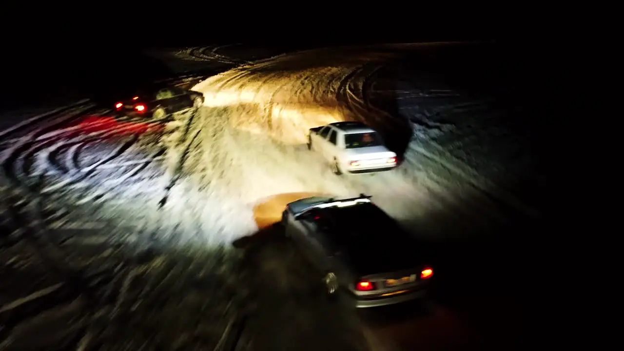 Aerial follow shot of extreme winter drift competition during nighttime