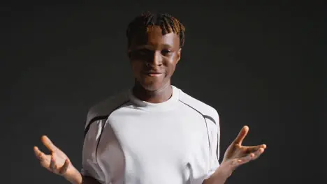 Low Key Studio Portrait Of Young Male Footballer Wearing Club Kit Celebrating Goal Miming Popular Goal Celebrations