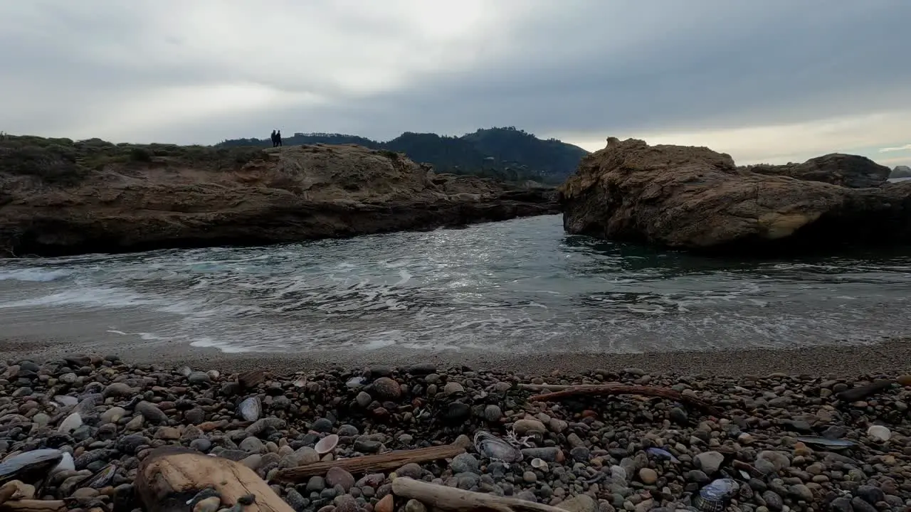 Ocean cove incoming waves with pebble beach rocks drift wood and seashells and sea shells