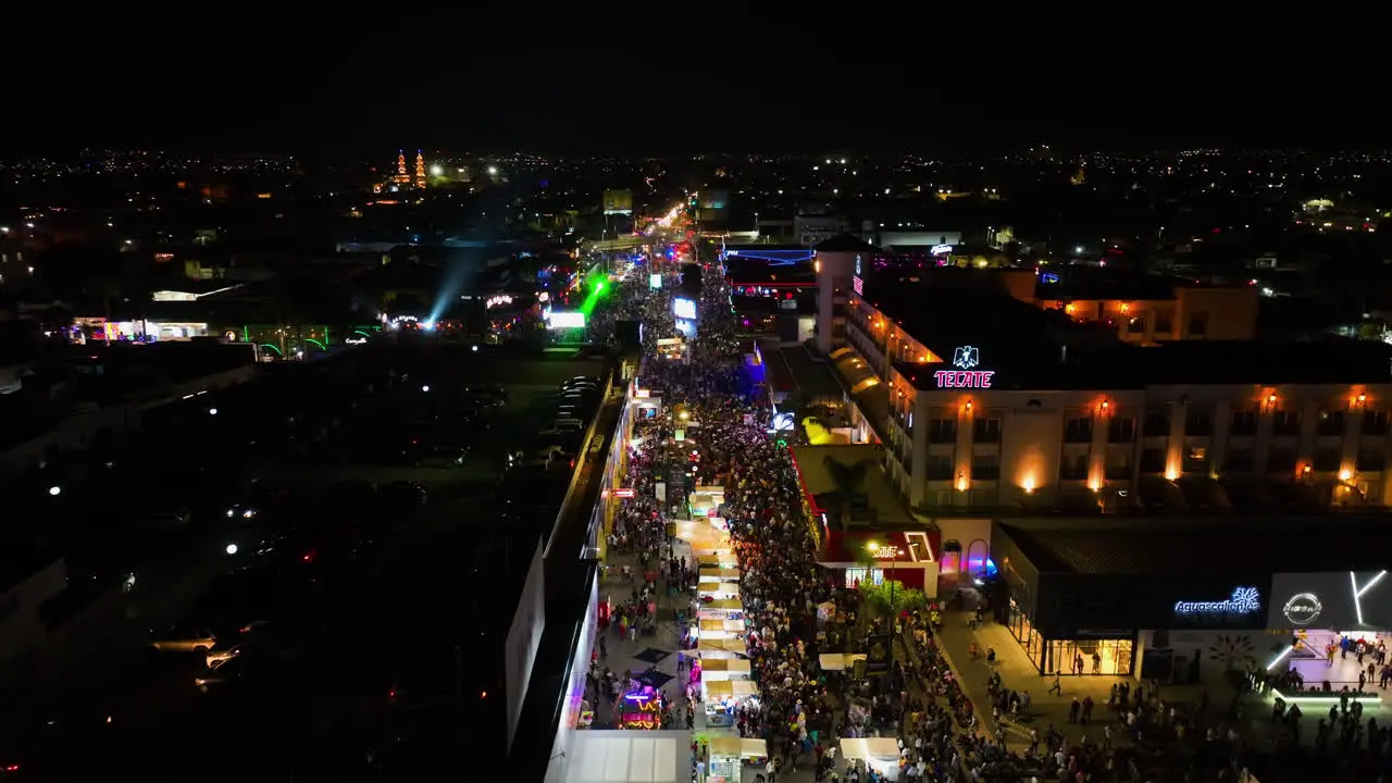 Drone shot panning over blinking night lit streets of Aguascalientes during the San Marcos fair