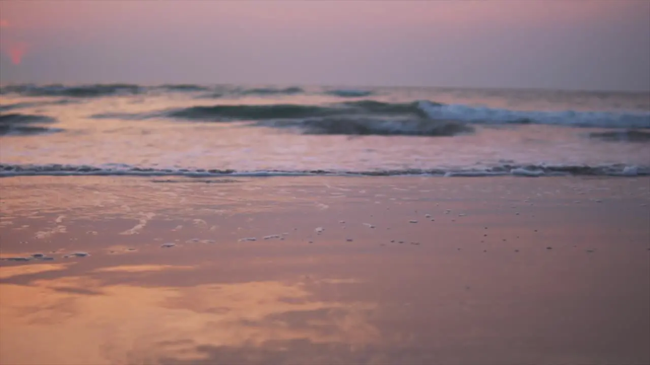 Waves splashing on beautiful beach that turned orange and pink because of the sunset