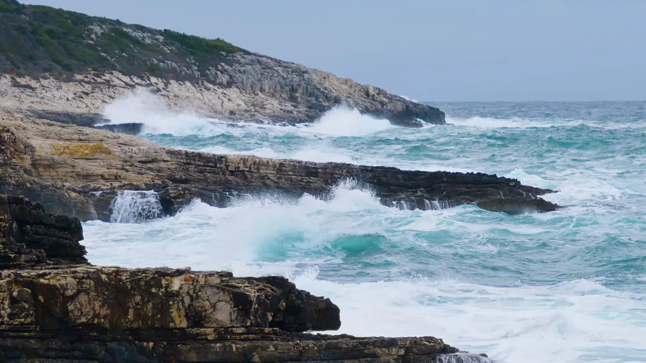 Sea waves breaking on rocky shore creating foam and mist on stormy weather