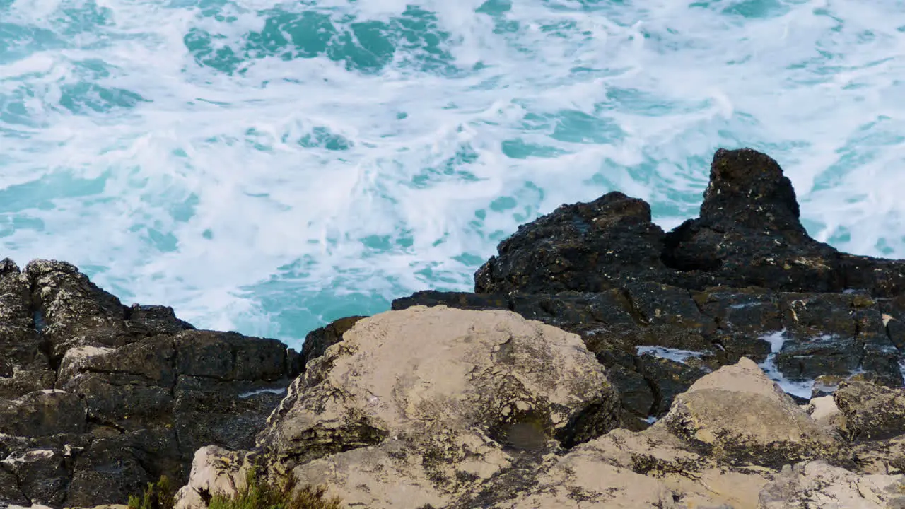 Sea waves breaks on rocky coast forming foam and mist