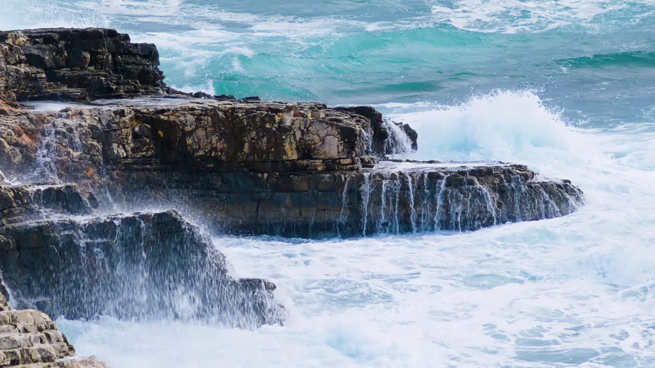 Sea waves breaking on rocky shore creating foam and mist on stormy weather medium