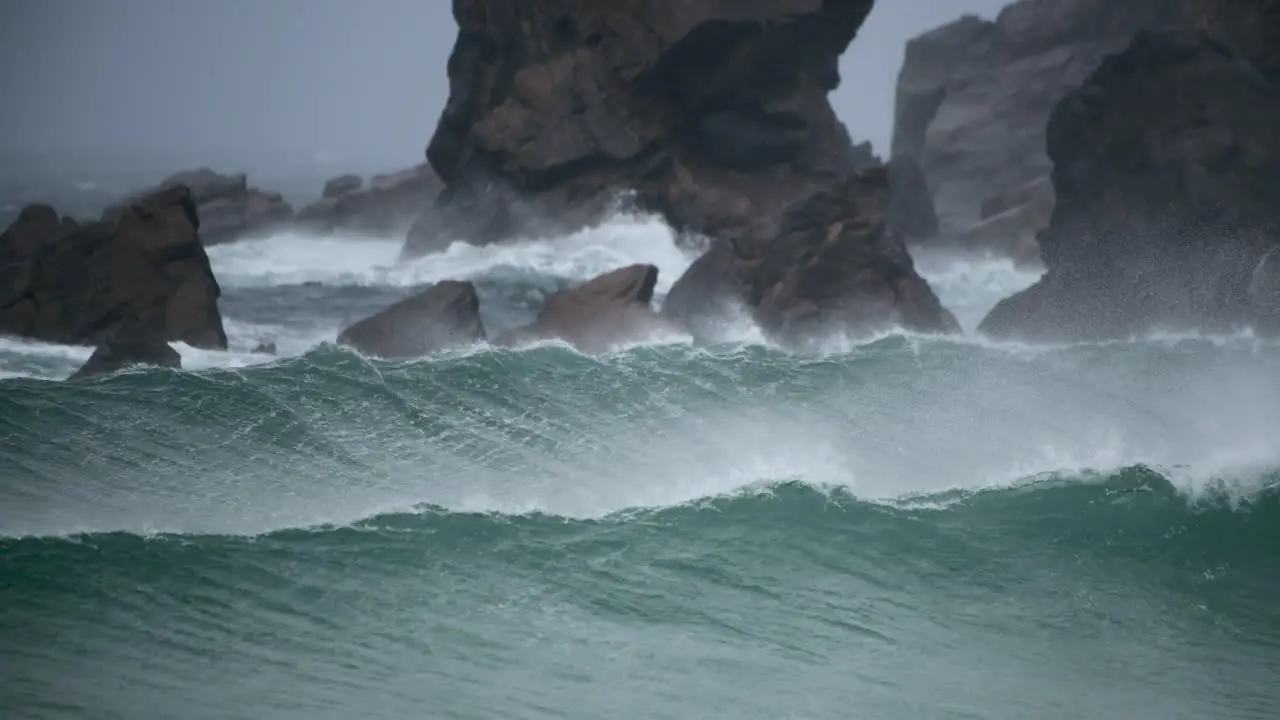 Perfect set of waves breaking along a rocky coastline with a strong offshore breeze in Scotland