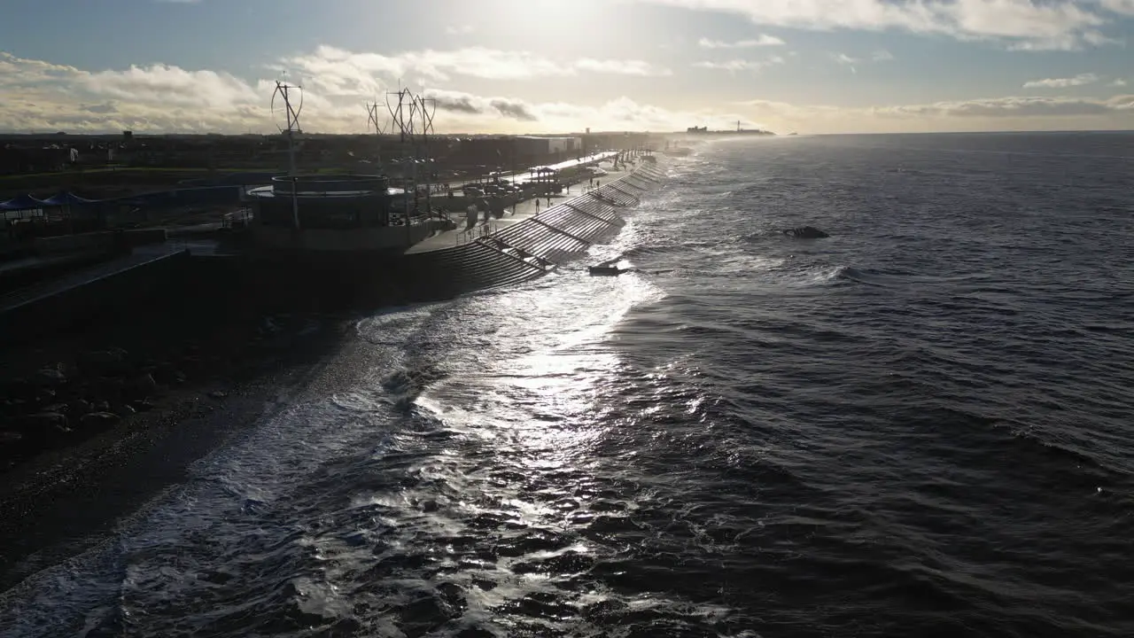 Slow motion waves crashing against sea defences with people walking in winter at Cleveleys