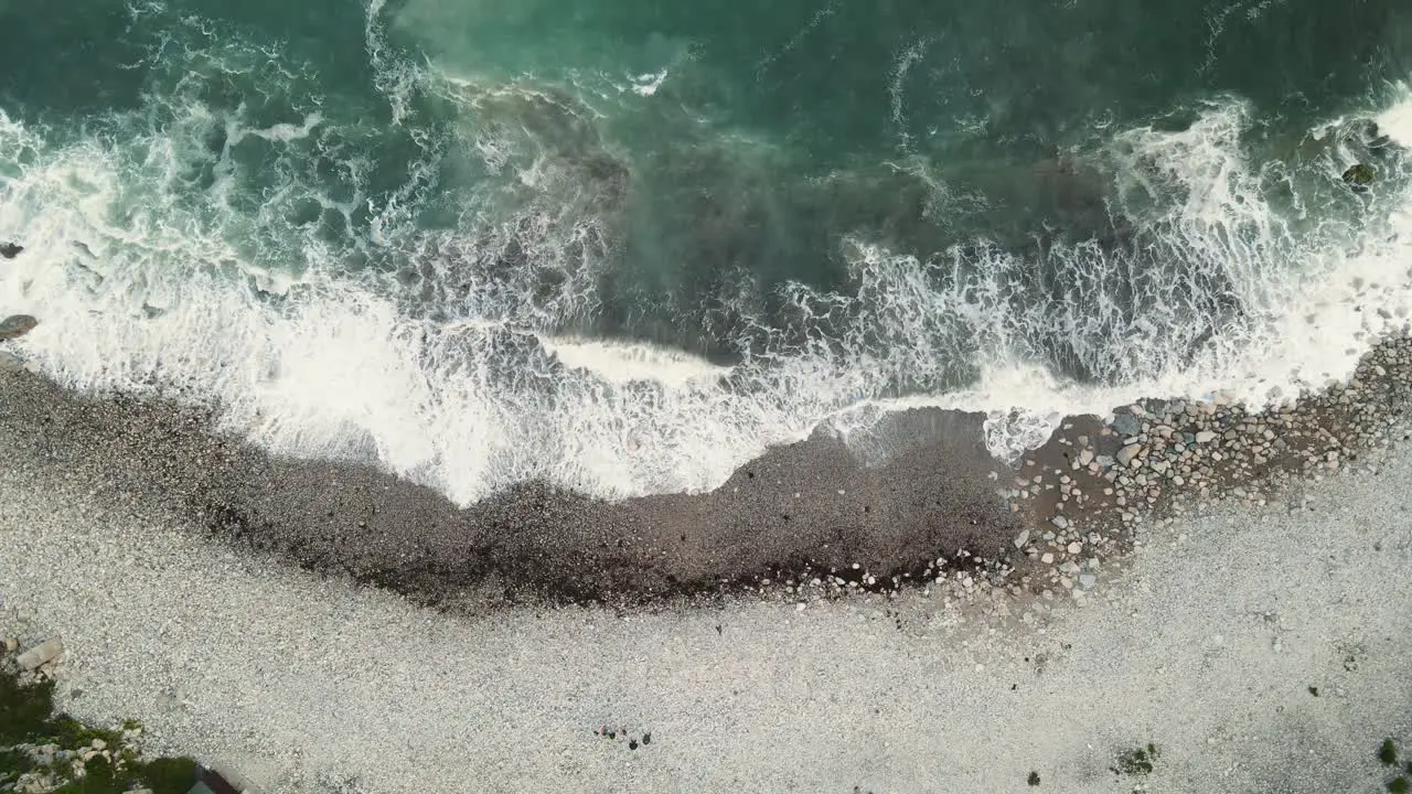 4K footage of a drone flying over the waves hitting the beach staying still