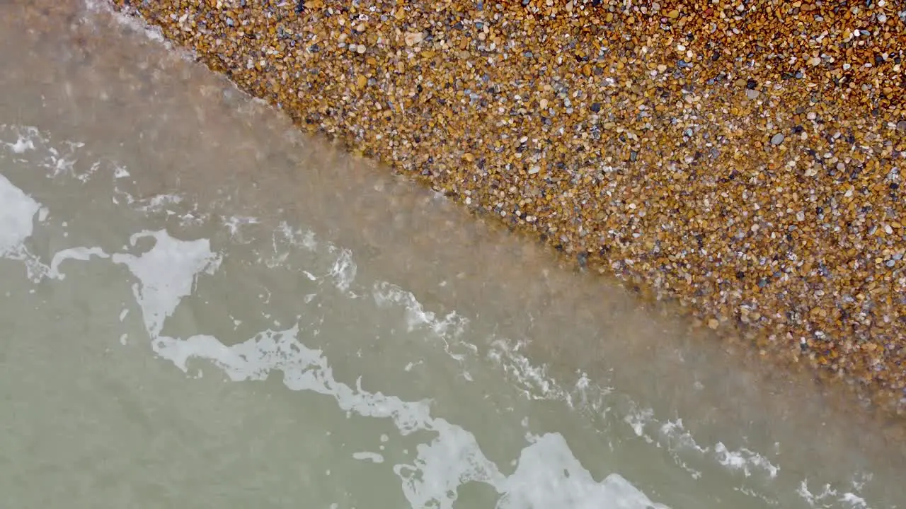 Relaxing footage of waves slowly lapping over shingle on a beach