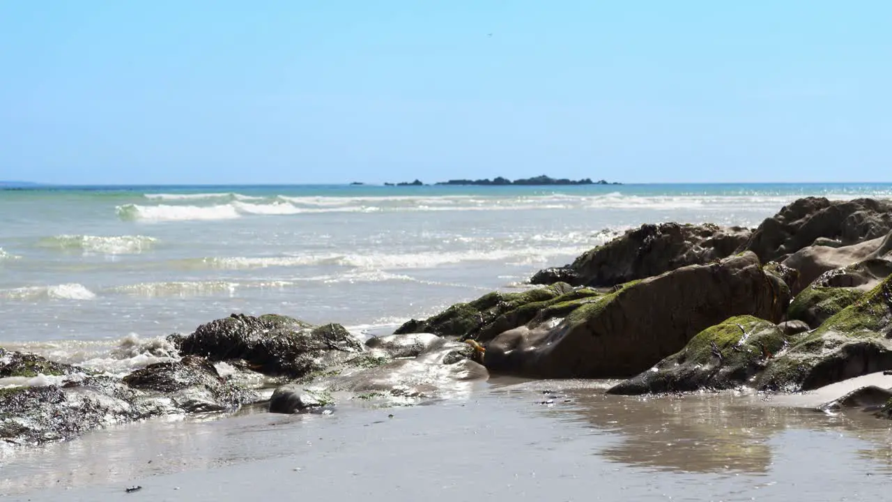 Waves wash over moss-covered rocks