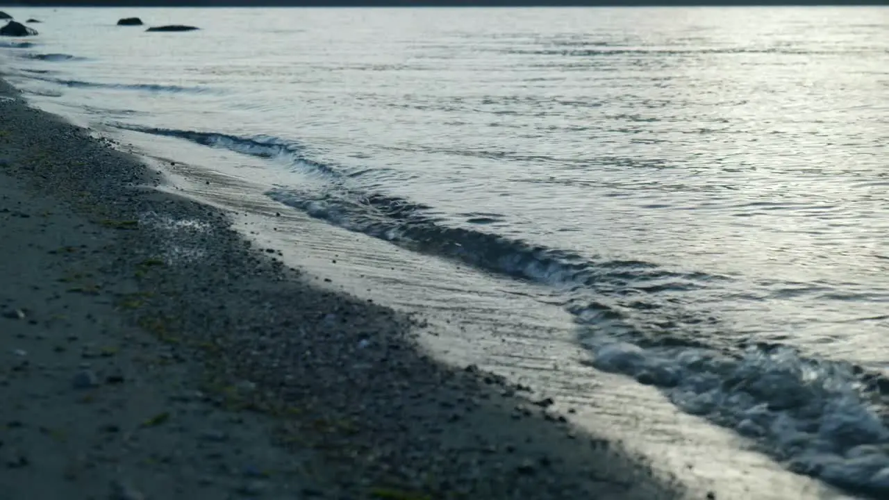 Intimate waves Close-up of waves breaking on a serene lake shore in captivating stock footage